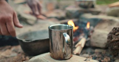 Turist gezisi sırasında tencereden metal bir fincana kahve doldurup hazırlamak..