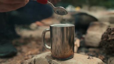 Turist gezisi sırasında tencereden metal bir fincana kahve doldurup hazırlamak..