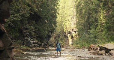 Aktif turist dağ nehri ile kayalık bir vadi boyunca yürür. Dağlarda aktif eğlence..