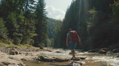 Dağ kanyonunda nehir boyunca yürüyen bir adamın hava görüntüsü. Dağ nehri boyunca tek bir turist yürüyüşü