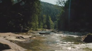 Dağ kanyonunda nehir boyunca yürüyen bir adamın hava görüntüsü. Dağ nehri boyunca tek bir turist yürüyüşü