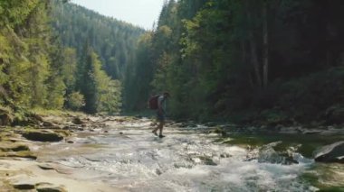 Dağ kanyonunda nehir boyunca yürüyen bir adamın hava görüntüsü. Dağ nehri boyunca tek bir turist yürüyüşü