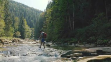 Dağ kanyonunda nehir boyunca yürüyen bir adamın hava görüntüsü. Dağ nehri boyunca tek bir turist yürüyüşü