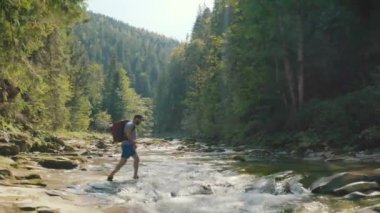 Dağ kanyonunda nehir boyunca yürüyen bir adamın hava görüntüsü. Dağ nehri boyunca tek bir turist yürüyüşü