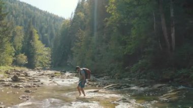 Dağ kanyonunda nehir boyunca yürüyen bir adamın hava görüntüsü. Dağ nehri boyunca tek bir turist yürüyüşü