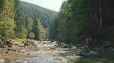 Dağ kanyonunda nehir boyunca yürüyen bir adamın hava görüntüsü. Dağ nehri boyunca tek bir turist yürüyüşü
