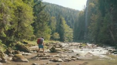 Dağ kanyonunda nehir boyunca yürüyen bir adamın hava görüntüsü. Dağ nehri boyunca tek bir turist yürüyüşü