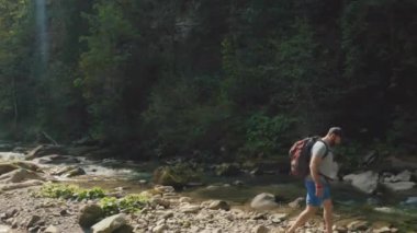 Dağ kanyonunda nehir boyunca yürüyen bir adamın hava görüntüsü. Dağ nehri boyunca tek bir turist yürüyüşü