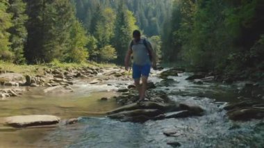 Dağ kanyonunda nehir boyunca yürüyen bir adamın hava görüntüsü. Dağ nehri boyunca tek bir turist yürüyüşü