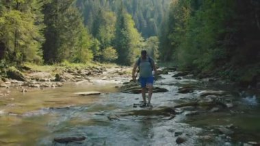 Dağ kanyonunda nehir boyunca yürüyen bir adamın hava görüntüsü. Dağ nehri boyunca tek bir turist yürüyüşü