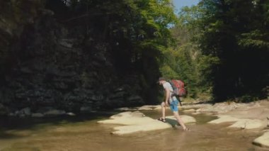 Dağ kanyonunda nehir boyunca yürüyen bir adamın hava görüntüsü. Dağ nehri boyunca tek bir turist yürüyüşü