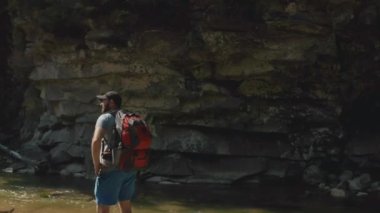 Dağ kanyonunda nehir boyunca yürüyen bir adamın hava görüntüsü. Dağ nehri boyunca tek bir turist yürüyüşü