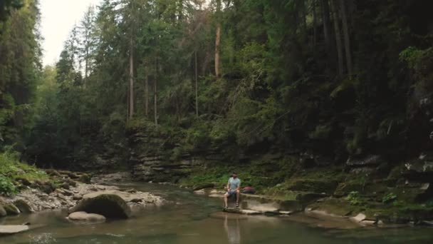 Viajante Solitário Repousa Sobre Uma Pedra Junto Rio Filmagem Drone — Vídeo de Stock