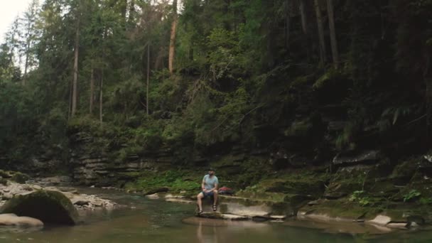 Viajante Solitário Repousa Sobre Uma Pedra Junto Rio Filmagem Drone — Vídeo de Stock