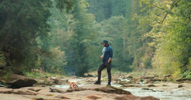 Ormanda kamp ateşinin yanında bir adam turist gezisi sırasında dinleniyor. Ormanda veya tek bir yolcunun dağlarında yürüyüş yapmak. Turist kampında bir turist.