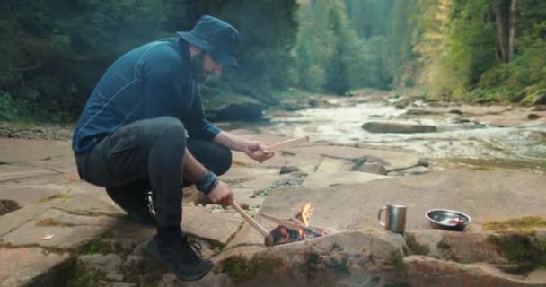 在森林篝火边 一名男性游客用一把小斧头砍柴 旅行者在准备生火的木柴 人在野外 野外远足者 野外生存 — 图库视频影像
