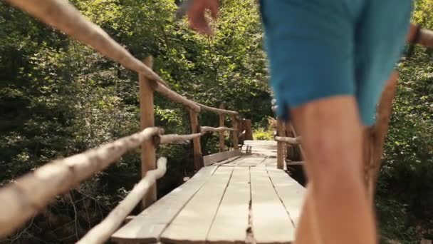 배낭을 하이킹 장비를 착용한 남자는 국립공원에서 서스펜션 다리를 건너다니며 산책합니다 — 비디오