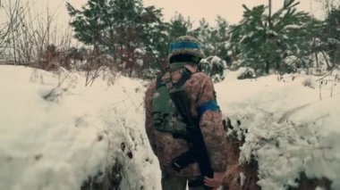 A soldier with a machine gun walks along the trench. A soldier in full armor walks along a trench. A soldier in the field. soldier with weapon in war.