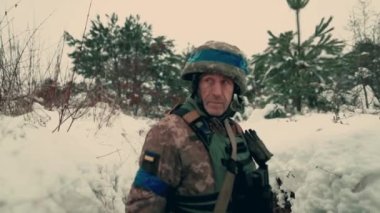 A soldier with a machine gun walks along the trench. A soldier in full armor walks along a trench. A soldier in the field. soldier with weapon in war.