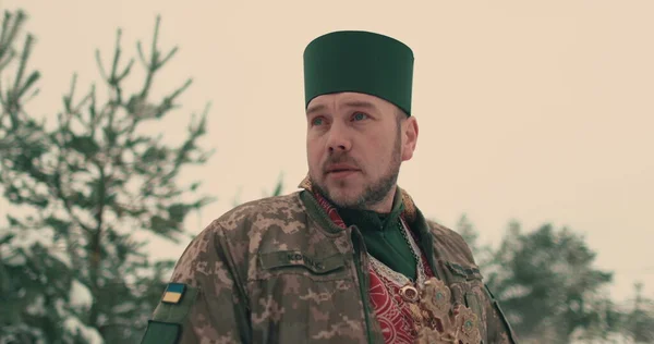 身穿乌克兰军队军装的牧师 一个年轻牧师在雪地的空旷空间中的画像 乌克兰与俄罗斯的战争 图库照片