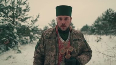 Ukrayna ordusunun askeri üniformalı papazı. Karlı bir alanda genç bir papazın portresi. Ukrayna 'nın Rusya ile savaşı.