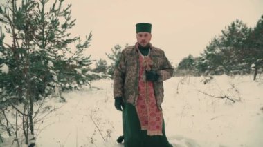 Ukrayna ordusunun askeri üniformalı papazı. Karlı bir alanda genç bir papazın portresi. Ukrayna 'nın Rusya ile savaşı.