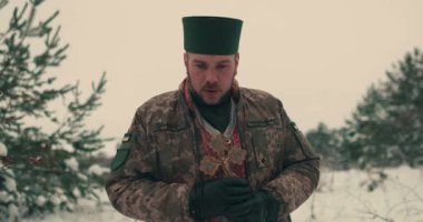 Ukrayna ordusunun askeri üniformalı papazı. Karlı bir alanda genç bir papazın portresi. Ukrayna 'nın Rusya ile savaşı.