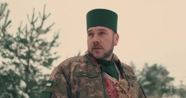 Ukrayna ordusunun askeri üniformalı papazı. Karlı bir alanda genç bir papazın portresi. Ukrayna 'nın Rusya ile savaşı.