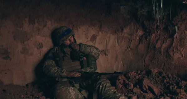 A Urain soldier sits on the bare ground in a dugout with a rosary in his hands and prays. Ukraine\'s war with Russia.
