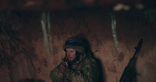 一名乌干达士兵双手拿着念珠坐在光秃秃的地面上祈祷 乌克兰与俄罗斯的战争 免版税图库图片