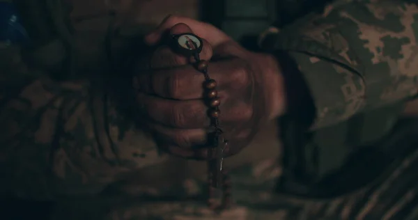 一只念珠在乌克兰士兵肮脏的手中的特写 一个士兵在失明中祈祷 图库图片