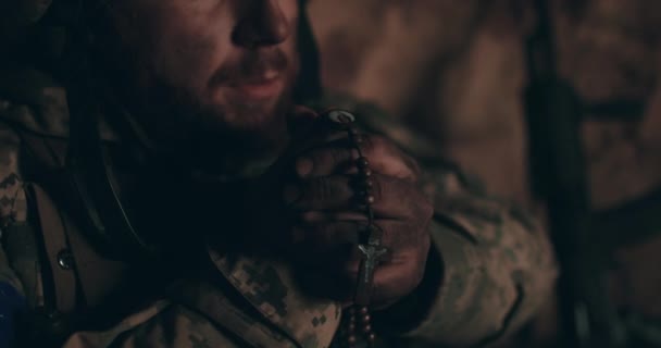 ウレインの兵士は 彼の手と祈りのロザリオで掘り出しに裸の地面に座っています ロシアとのウクライナ戦争 — ストック動画