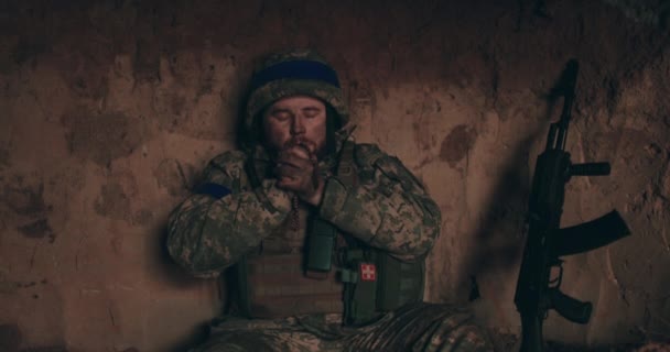 ウレインの兵士は 彼の手と祈りのロザリオで掘り出しに裸の地面に座っています ロシアとのウクライナ戦争 — ストック動画
