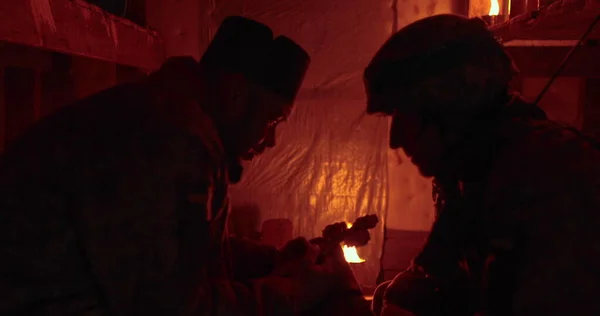 一名乌克兰士兵在黑暗的昏暗中认罪 牧师和典狱长面对面地坐着谈话 图库图片