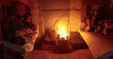 Yanan bir siper mumunun ışığında iki asker sığınakta yatıyor. Sığınakta Ukraynalı asker.