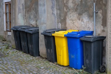 Multicolored trash cans for separated waste on a stone street in the city.