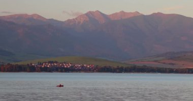 Gün batımında yüzen küçük bir tekneyle dağ ve göl manzarası. Slovakya 'daki Batı Tatras dağlı Liptovska Mara Gölü. Avrupa.