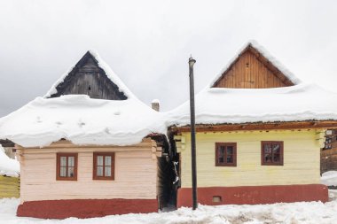 Karlı kış manzarasında halk mimarisi. Tarihi renkli ahşap evleri olan Vlkolinec köyü, Slovakya Avrupa.