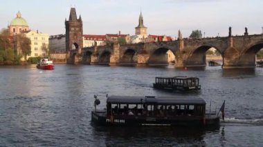 PRAG, CZECH REPUBLIC - 6 MAYIS 2023: Vltava nehrinde gün batımında tekneli Charles Köprüsü.