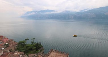 Arka planda dağlar olan Garda Gölü 'ndeki tekne, gölün doğu kıyısındaki Malcesine kasabasından manzara, İtalya, Avrupa.