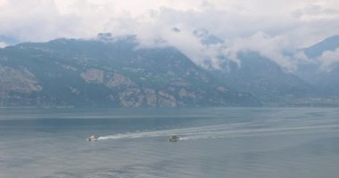 Arka planda dağlar olan Garda Gölü 'ndeki tekneler, gölün doğu kıyısındaki Malcesine kasabasından manzara, İtalya, Avrupa.