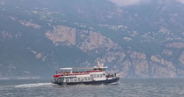 MALCESINE, İTALYA - 30 Mayıs 2024: arka planda dağlarla Garda Gölü 'nde tekne.