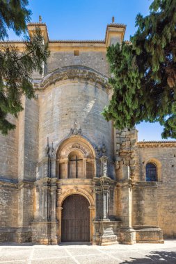 İspanya 'nın Ronda kasabası. Açık mavi gökyüzünün altındaki antik taş kilise girişi. Karmaşık detaylar ve eski ahşap kapı.