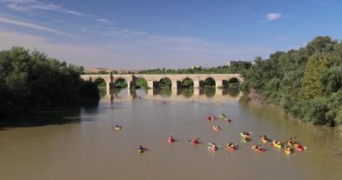 İspanya 'nın Cordoba kasabasındaki Roma köprüsünün altında yemyeşil sularla çevrili sakin bir nehirde kanocular kürek çekiyor..