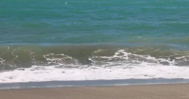 Nerja kasabası, İspanya 'nın güneyinde Endülüs' ün deniz kıyısında bir tatil beldesi. Okyanus dalgaları yavaşça kumlu bir plaja yuvarlanıyor. Sakin bir sahil manzarası. Yavaş çekim görüntüleri.