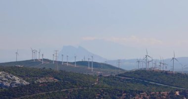 Yamaçta rüzgar türbinleri, dağ zemininde temiz enerji. Arka planda Cebelitarık Kayası.