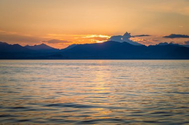 Günbatımında arka planda dağlar olan Garda Gölü Lazise kenti kıyılarından, İtalya, Avrupa manzarası.