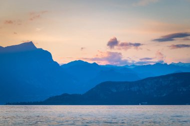 Günbatımında arka planda dağlar olan Garda Gölü Lazise kenti kıyılarından, İtalya, Avrupa manzarası.