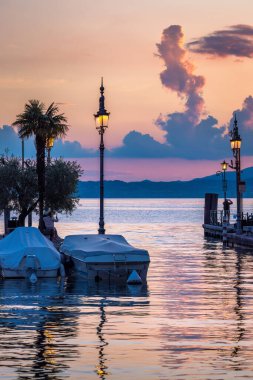 Lit lamps on the shores of Lake Garda in the early evening, Lazise town, Italy, Europe. clipart