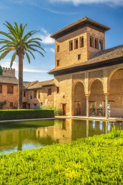 Alhambra kompleksindeki Partal Sarayı Granada, Endülüs, İspanya. Yansıtıcı havuzu, geleneksel mimarisi ve gür yeşilliği olan sakin bir avlu..